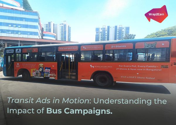 A city bus wrapped with colorful advertising from Wrap2Earn, moving through a busy urban street.